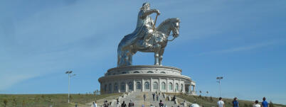 Chinggis Khaan Equestrian Statue Complex with tourists on the steps against a blue sky.