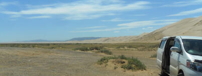 Tourist minivan in front of sand dunes