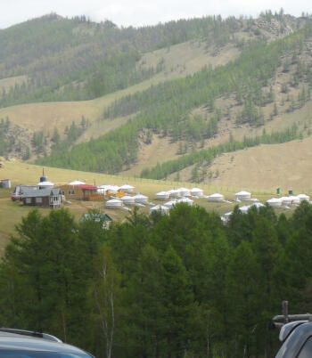 A tourist ger camp in Terelj National Park, with rows of traditional white Mongolian gers arranged on a green valley floor.